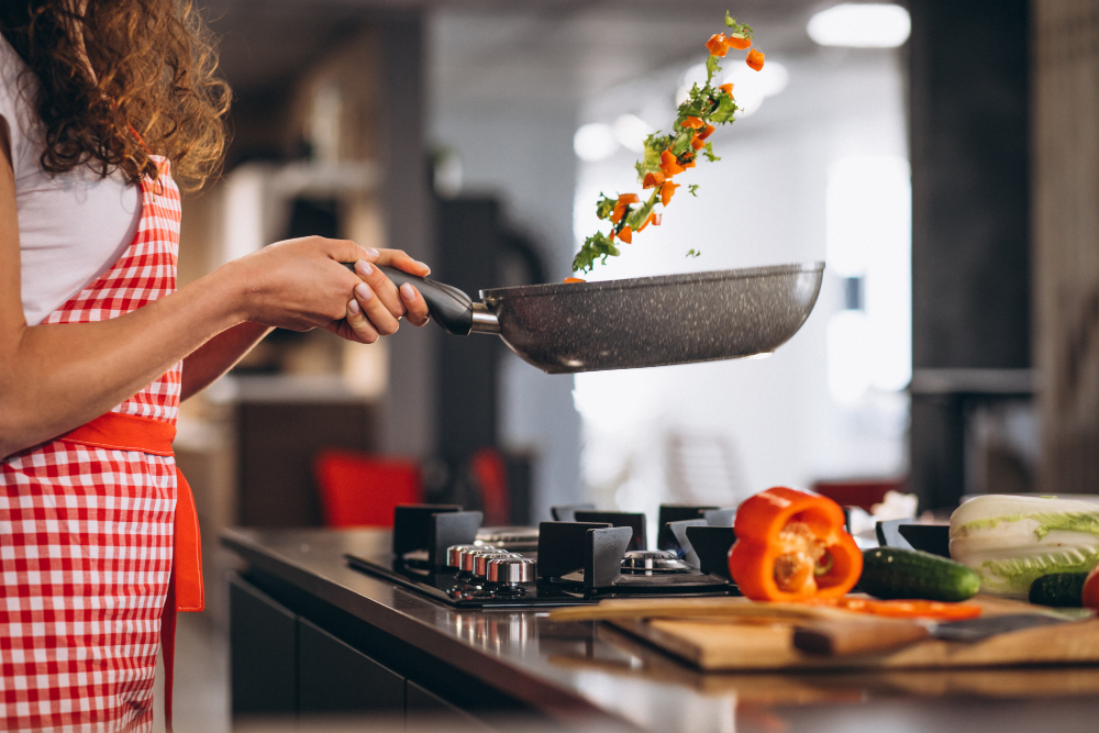 Une femme cuisant des légumes dans une poële