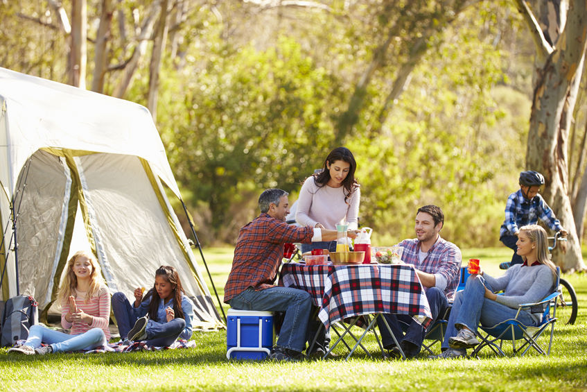 des personnes mangeant un repas à côté d'une tente de camping