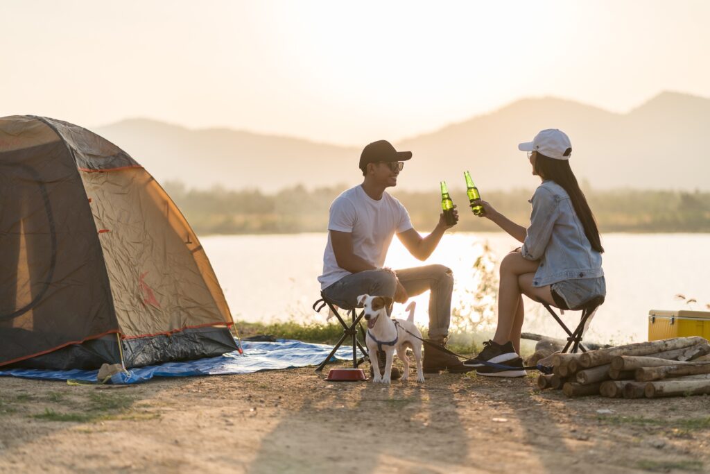 deux personnes buvant une bière devant une tente de camping