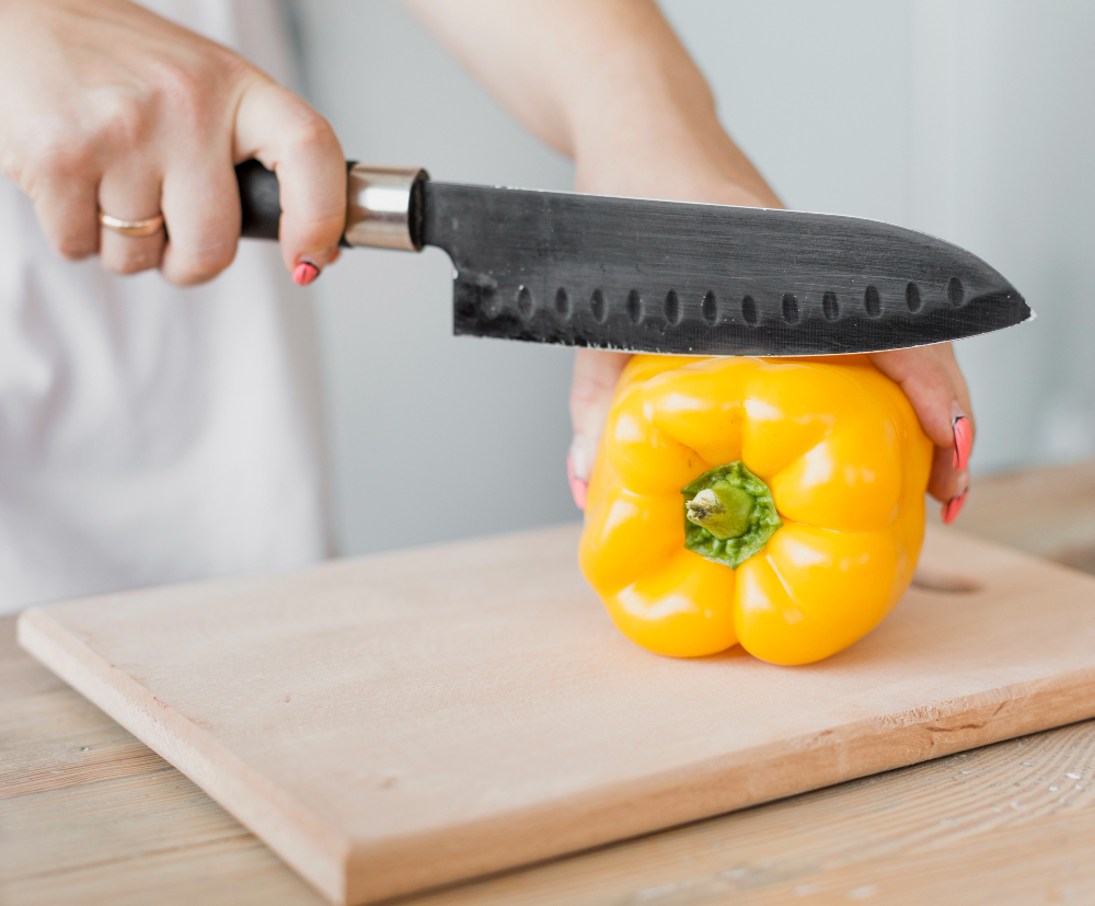 une femme coupant un poivron jaune