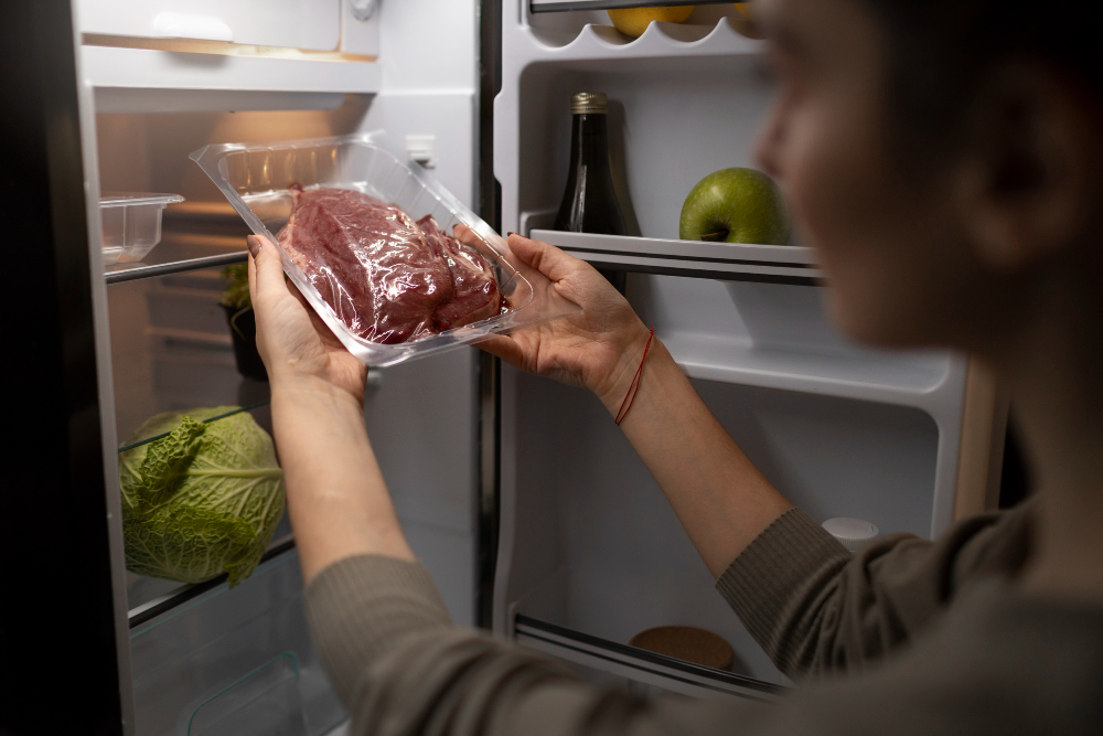 une femme rangeant une viande sous vide dans son frigo