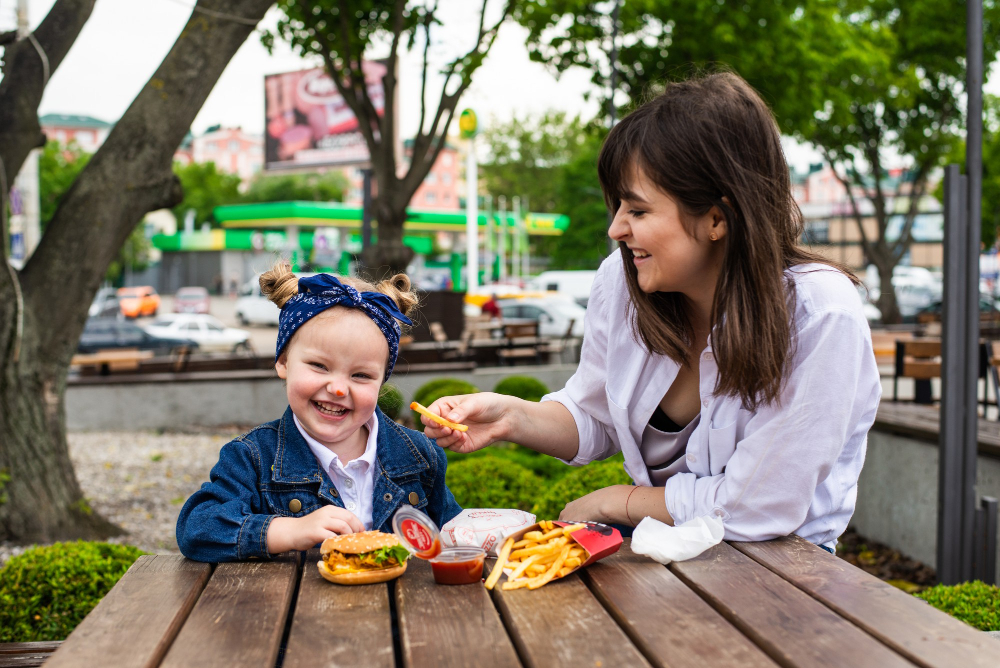 une mère et sa fille mange un fastfood en terrasse