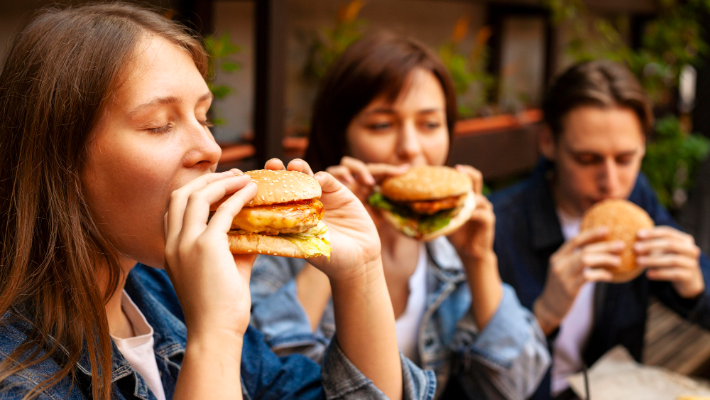 trois personnes qui mangent un burger