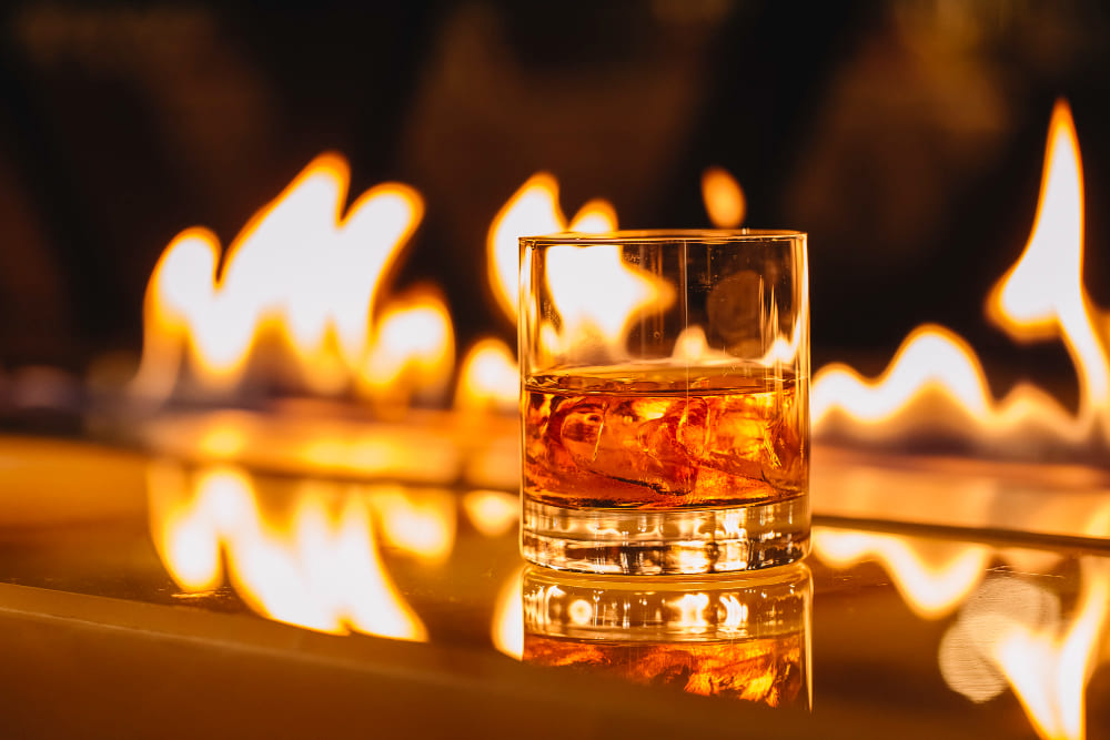 Verre de whisky près d'un feu de cheminée