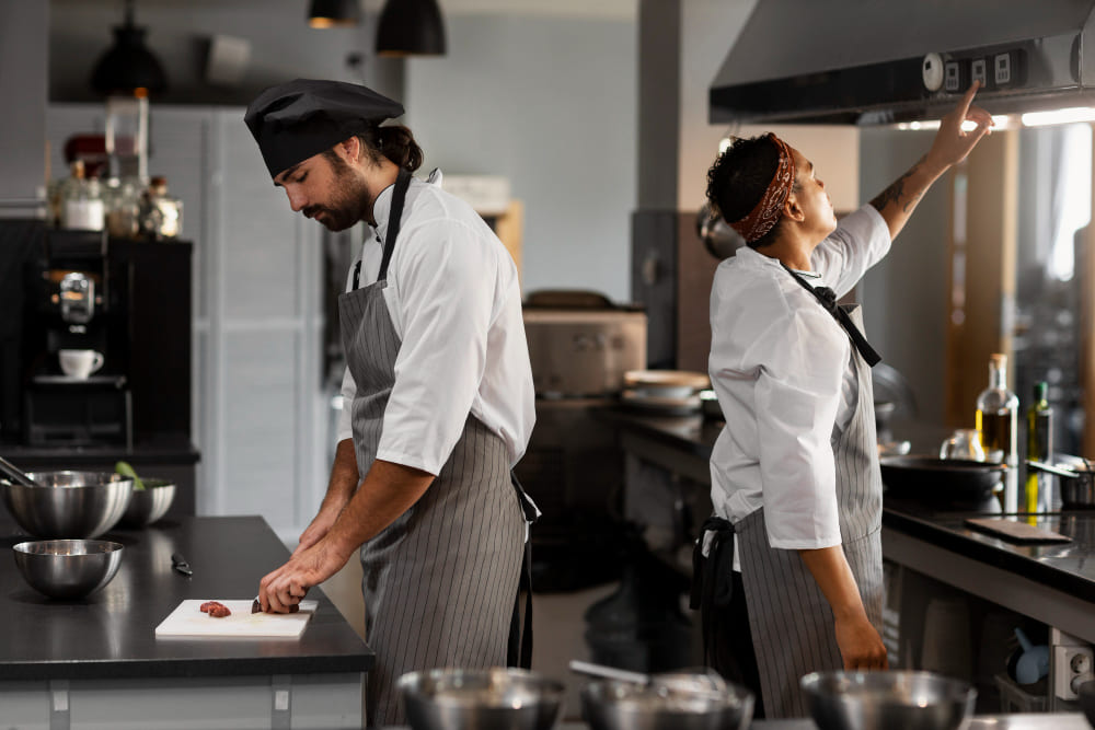 Chef réglant une hotte sans moteur dans une cuisine professionnelle de restaurant