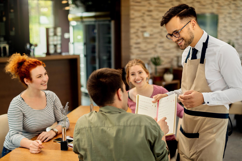 Un serveur présente une carte de restaurant a des clients